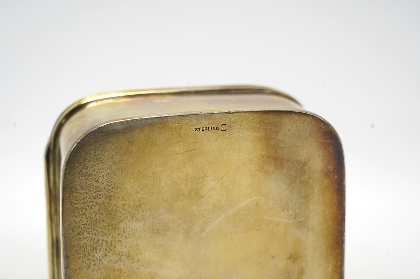 An American sterling trinket box with hinged cover and foliate scroll decoration, engraved with monogram, 13.4cm, gross weight 300 grams. Condition - fair